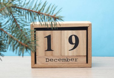 Ahşap blok takvimi ile tarih 19 Aralık ve masa ve mavi arkaplanda çam ağacı
