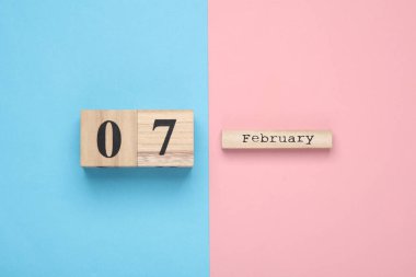 Tahta blok takvimi. Pembe mavi pastel arka plan üzerinde tarih 07 Şubat. Üst Manzara. Düz yatıyordu