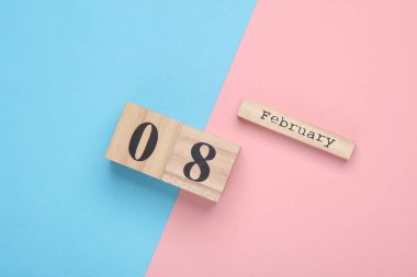 Ahşap blok takviminde tarih 08 Şubat, pembe mavi pastel arka plan. Üst Manzara. Düz yatıyordu