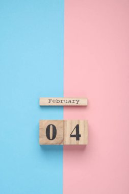Ahşap blok takvimi ve pembe mavi pastel arka planda tarih 04 Şubat. Üst Manzara. Düz yatıyordu