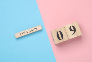 Ahşap blok takviminde tarih 09 Şubat, pembe mavi pastel arka plan. Üst Manzara. Düz yatıyordu