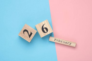 Ahşap blok takvimine göre tarih 26 Şubat, pembe mavi pastel arka plan. Üst Manzara. Düz yatıyordu