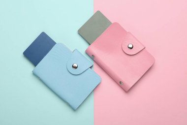 Pembe mavi arka planda kredi kartları olan deri cüzdanlar. Üst görünüm