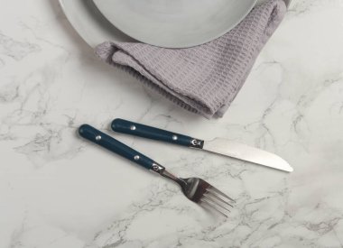 Tabaklar, mermer zemin üzerinde havlu olan çatal bıçak takımı. Tablo ayarı