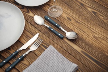 Ahşap arka planda sofra takımı için tabak ve çatal bıçak takımı.