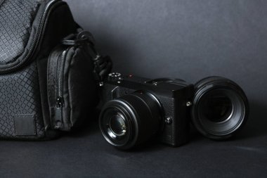 Profesyonel bir fotoğrafçının ekipmanı. Kameralı fotoğraf çantası ve siyah arka planda lens.