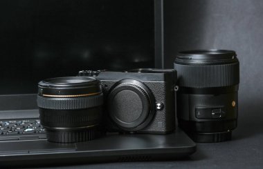 Laptop ve siyah arka planda lensleri olan profesyonel kamera. Fotoğrafçı ya da kameraman için ekipman