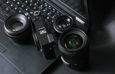 Laptop ve siyah arka planda lensleri olan profesyonel kamera. Fotoğrafçı ya da kameraman için ekipman