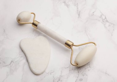 Yeşim yüz silindiri ve mermer arka planda gua sha kazıyıcı. Güzellik konsepti