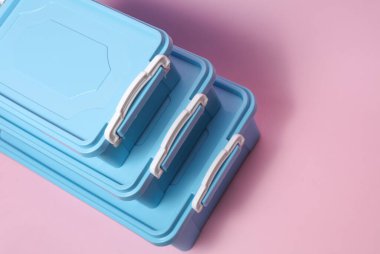 Pembe arka planda yiyecek depolamak için plastik kaplar.