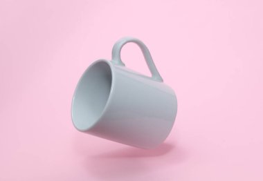 Pembe arka planda yüzen beyaz seramik bardak