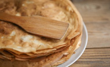 Masada ahşap bir spatulayla tabakta bir yığın krep.