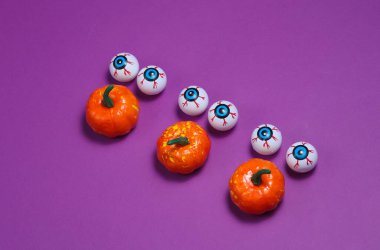 Mor arka planda balkabağı olan gözler. Minimalist Cadılar Bayramı natürmort