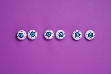 Mor bir arka planda gözler. Minimalist Cadılar Bayramı natürmort