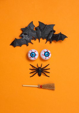 Cadılar Bayramı, turuncu arka planda bir yüz şeklinde dekorla sakin bir hayattır.