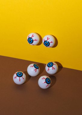 Sarı kahverengi arka planda gözler. Minimalist cadılar bayramı hala hayattadır. Yaratıcı yerleşim