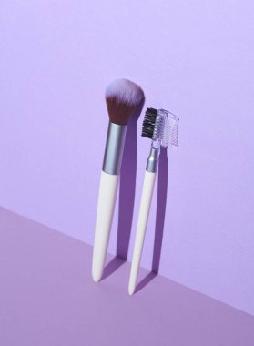 Mor arka planda makyaj fırçaları. Yaratıcı düzen. Güzellik gölgeli bir hayat