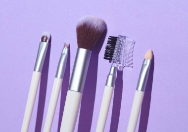 Mor arka planda makyaj fırçaları. Yaratıcı düzen. Güzellik gölgeli bir hayat