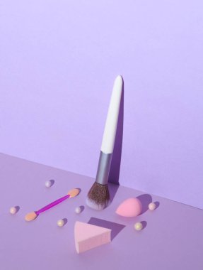 Mor arka planda dekoratif kozmetik ürünleri için fırçalar ve aksesuarlar