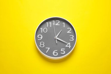 Sarı arkaplanda büyük yuvarlak duvar saati
