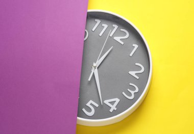 Mor sarı arkaplanda büyük yuvarlak duvar saati