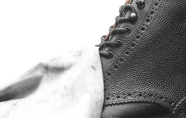 Beyaz arka planda bez parçası olan siyah çizmeler. Deri ayakkabıların bakımını ve temizliğini