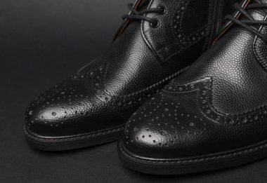 Siyah arka planda siyah deri erkek çizmeleri.