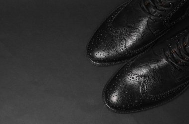 Siyah arka planda siyah deri erkek çizmeleri.