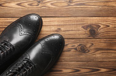 Ahşap arka planda şık siyah deri erkek çizmeleri. Üst Manzara. Düz yatıyordu