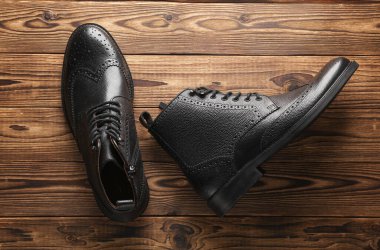 Ahşap arka planda şık siyah deri erkek çizmeleri. Üst Manzara. Düz yatıyordu