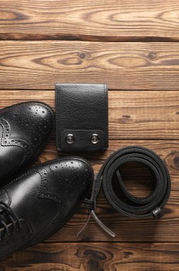 Erkek siyah deri botları, cüzdanı ve kemeri tahta arka planda. Üst vew