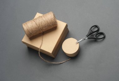 DIY, Ürün ambalajlama, sunum. Kraft karton kutular ile makas ve iplik koyu gri arkaplan.