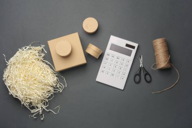 DIY, Ürün ambalajlama, sunum. Doldurucu, makas ve iplik içeren Kraft karton kutular, koyu gri arkaplan üzerinde hesap makinesi.