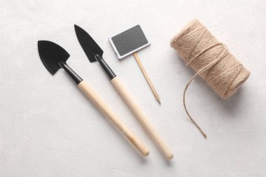 Minyatür bahçe aletleri, iplik izi ve beton arka planda bir etiket. Düz yatıyordu