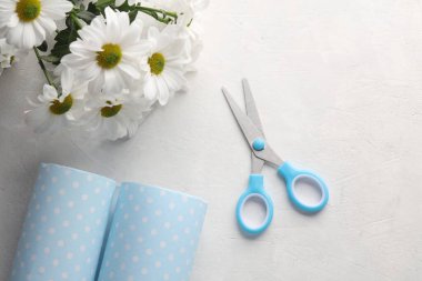 Beton bir arka planda çiçek buketi ve makas ile ambalaj kağıdı. Üst görünüm