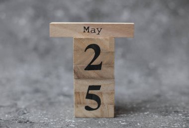 Koyu beton zemin üzerinde tarihi 25 Mayıs olan tahta blok takvimi