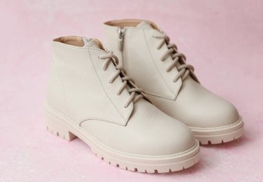 Pembe beton arka planda beyaz kadın deri çizmeleri.