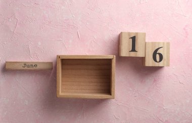 Tahta blok takvimi ve pembe beton arka planda tarih 16 Haziran