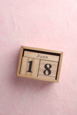 Ahşap blok takvimi ve pembe beton arka planda tarih 18 Haziran