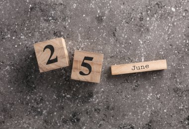 Koyu beton arkaplan üzerine tahta blok takvimi 25 Haziran