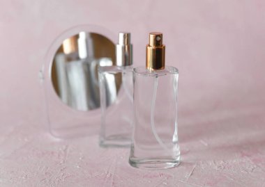 Pembe arka planda ayna olan parfüm şişeleri