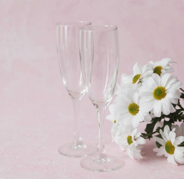 İki boş bardak ve pembe beton arka planda bir buket çiçek.