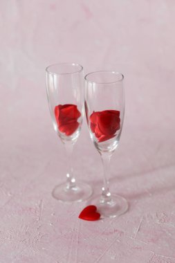 Pembe arka planda kırmızı kalpli iki bardak.