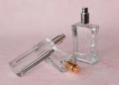 Üç cam parfüm ya da pembe beton arka planda Eau de Tuvalet şişeleri