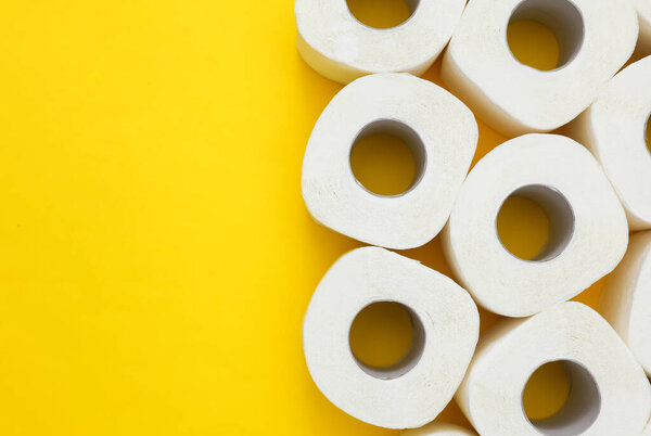 Lots of toilet paper rolls on yellow background. Top view