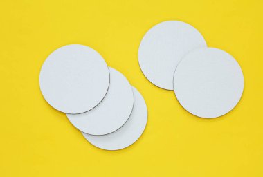 Sarı zemin üzerindeki bardak ya da bardaklar için beyaz boş bardak altlıklarının maketi