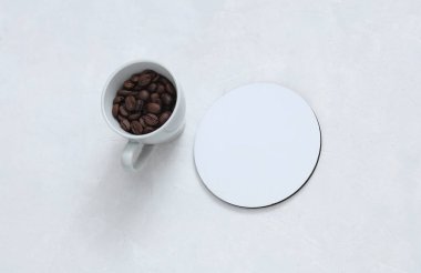 Beyaz yuvarlak boş bardak altlıkları. Beyaz beton arka planda kahve çekirdekleri.
