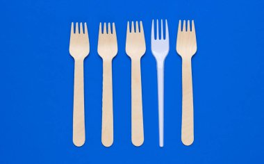 Minimalist çevre kavramı. Ahşap ve plastik çatallar mavi arka planda. Yaratıcı ekolojik altyapı. Üst görünüm