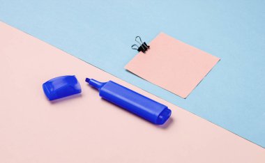 Kırtasiye malzemeleri. Kağıt ataç, keçeli kalem, pembe mavi pastel üzerine not kağıdı arka plan.