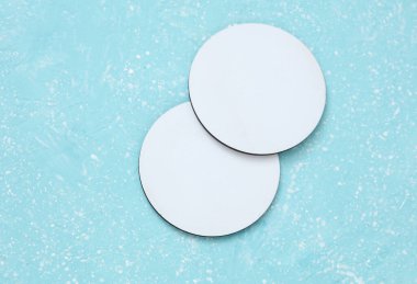 Bardak altlıkları, mavi beton arka planda beyaz yuvarlak modeller.